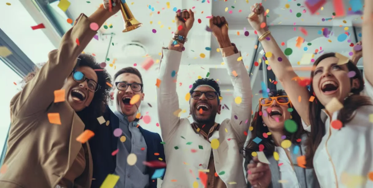 A diverse team of five people celebrating with confetti falling, raising their arms in joy after receiving clear user research results