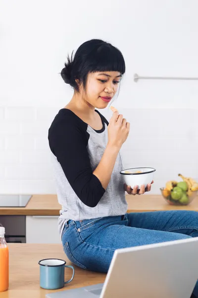 Woman sitting in her kitchen browsing paid research opportunities on her laptop
