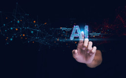 Hand reaching toward a glowing 'AI' text surrounded by a network of digital nodes and glowing points, symbolizing artificial intelligence and connectivity.